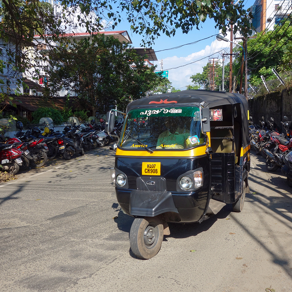 A black and yellow rickshaw taxi driving down a street.